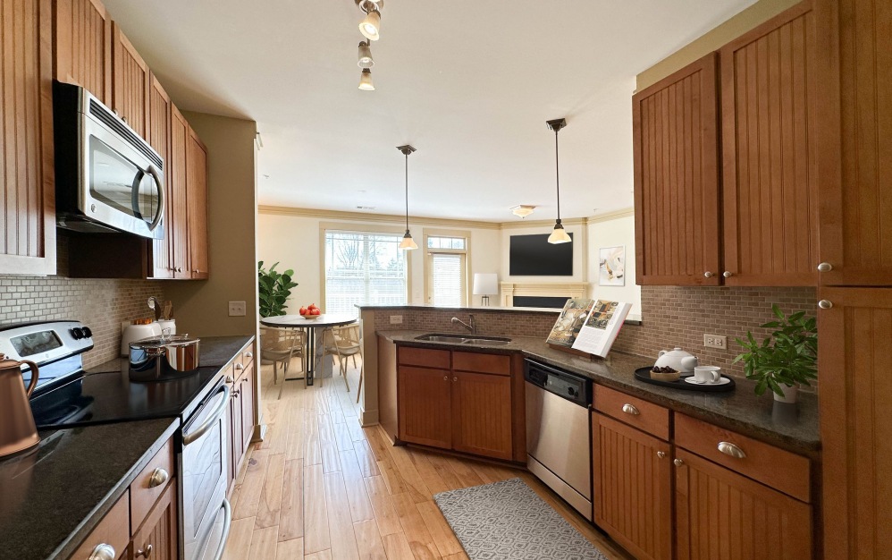 Large apartment kitchen with wood cabinets, granite countertops, and stainless steel appliances at Cosgrove Hill